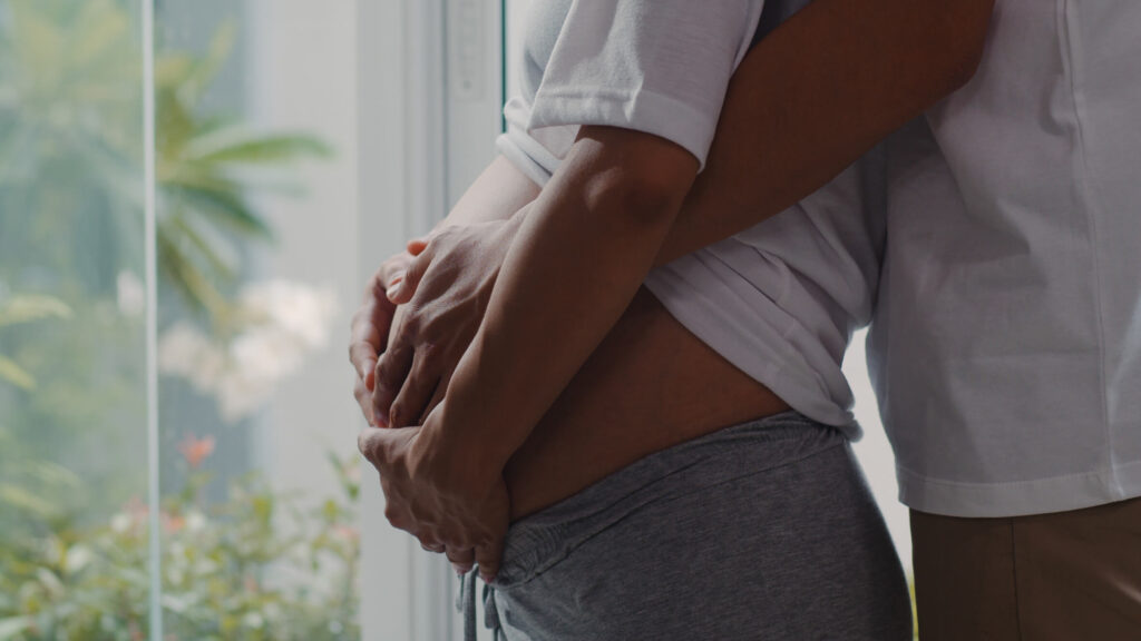 young-asian-pregnant-couple-hug-holding-belly-talking-with-their-child-mom-dad-feeling-happy-smiling-peaceful-while-take-care-baby-pregnancy-near-window-living-room-home (1)